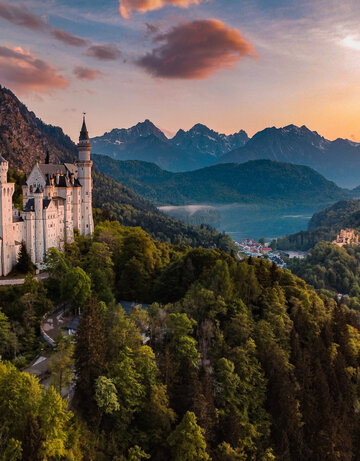 Das Bild fängt das majestätische Schloss Neuschwanstein im Sonnenuntergang ein, im Hintergrund Schloss Hohenschwangau und der Alpsee