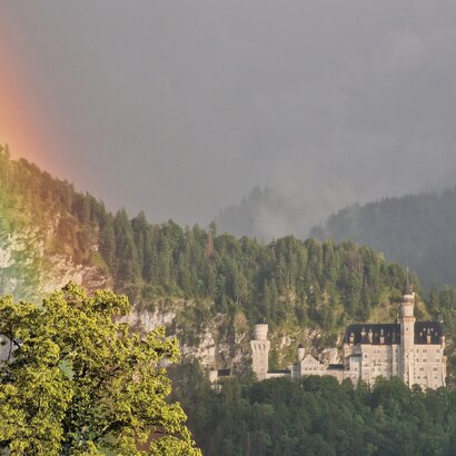 Das Foto zeigt Schloss Neuschwanstein bei Füssen im Allgäu mit einem Regenbogen.