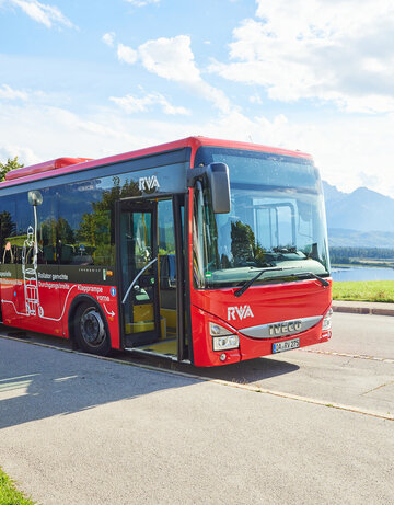 Foto eines Nahverkehrs-Busses mit dem Forggensee und den Ammergauer Alpen im Hintergrund