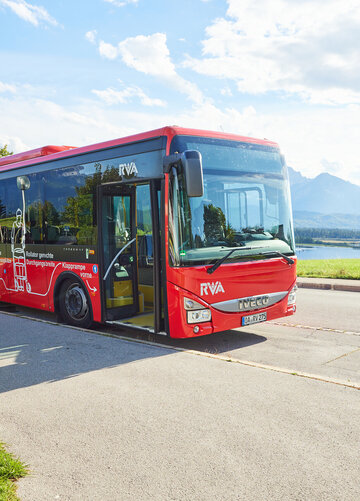 Foto eines Nahverkehrs-Busses mit dem Forggensee und den Ammergauer Alpen im Hintergrund