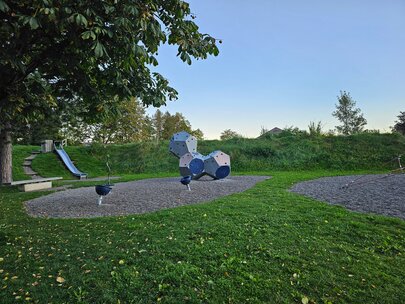 Auf dem Bild sieht man eine Rutsche und weitere Spielelemente eines Spielplatzes.