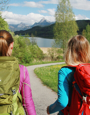 Ein Paar wandert entlang des Weißensees bei Füssen in der Löwenzahnblüze