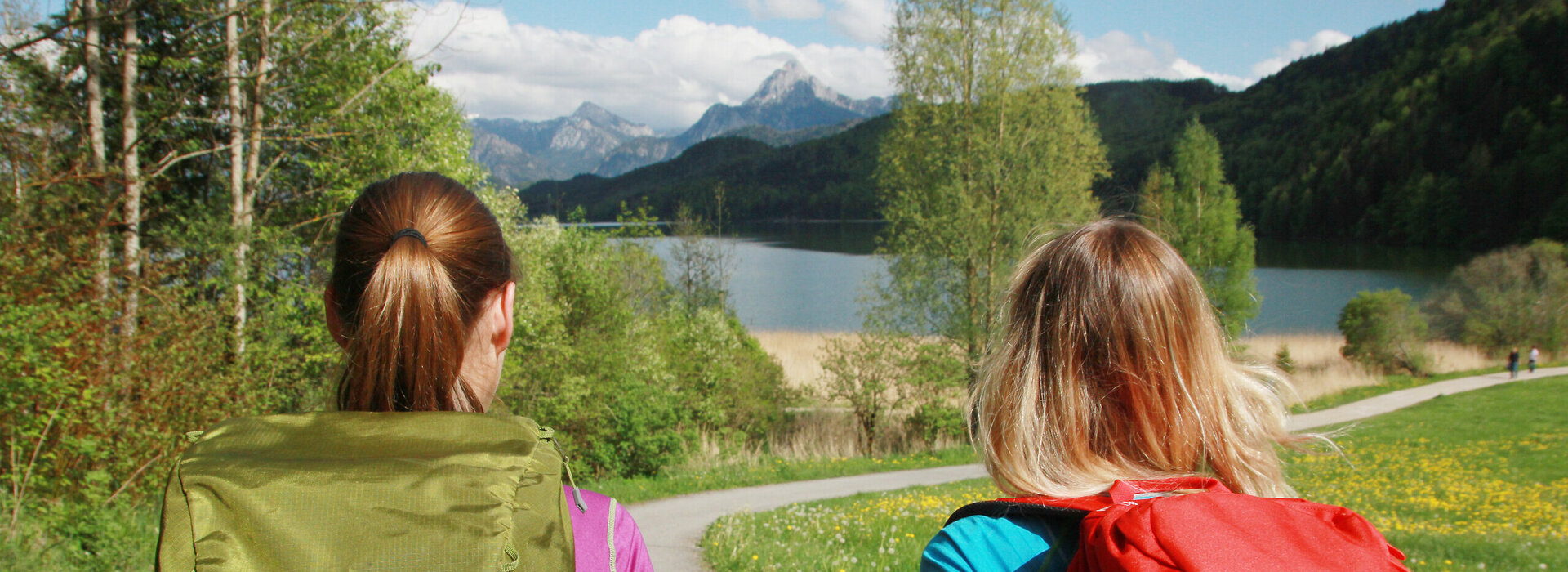 Ein Paar wandert entlang des Weißensees bei Füssen in der Löwenzahnblüze